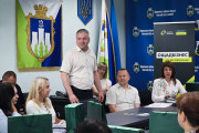 Людина виступає перед аудиторією, на тлі банерів "Ощадбізнес" та символіки міста.